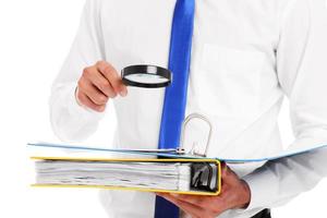 Midsection of a businessman searching documents with magnifying glass photo