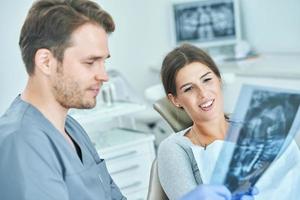 Male dentist and woman discussing x-ray results in dentist office