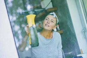 mujer joven limpiando la ventana en la cocina foto