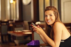 Pretty woman using smartphone in restaurant photo