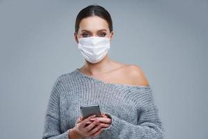 Portrait of beautiful woman in mask on gray background photo