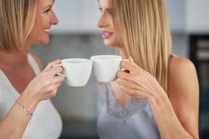 Nice two adult girls in the kitchen with coffee photo