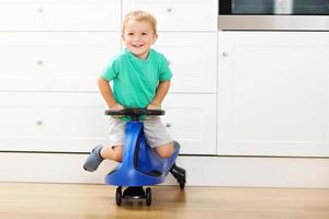 Happy little boy having fun and driving toy race car at home photo