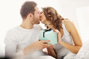 Young couple with present in bed photo