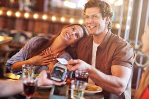 Cute couple on a date at the cafe paying by credit card photo