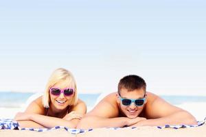 pareja joven tomando el sol en la playa foto