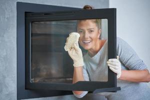 Picture of young woman cleaning fireplace glass doors photo