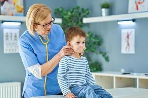 Pediatrician doctor examining little kids in clinic photo