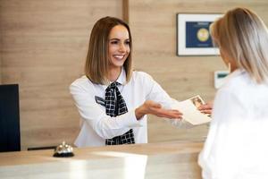 Receptionist and businesswoman at hotel front desk photo