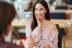 Young man proposing to his girlfriend in a cafe photo