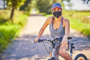 mujer joven en bicicleta en el campo con una máscara foto