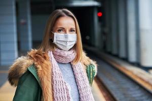 Adult woman at train station wearing masks due to covid-19 restrictions