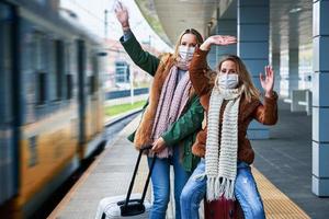 dos mujeres en la estación de tren con máscaras debido a las restricciones de covid-19 foto