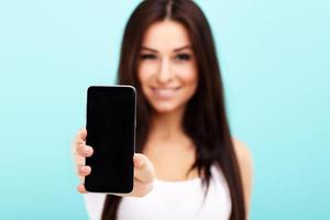 Woman using smartphone against blue wall background photo