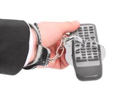 TV addict concept with person handcuffed with remote photo