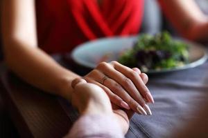 pareja comiendo una cena romántica en un restaurante gourmet bebiendo vino y tomándose de la mano foto