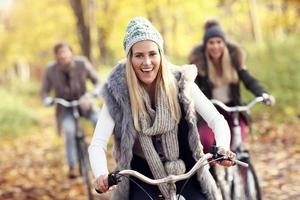 grupo de amigos en bicicleta en el bosque durante el otoño foto