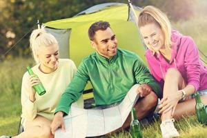 Group of friends camping in forest and looking at map photo