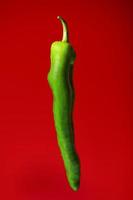 Green pepper on red background photo