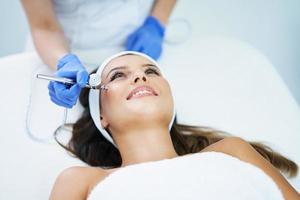 Beautiful young woman getting face treatment at beauty salon. photo