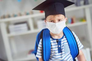 Adorable little boy in kindergarten with mask on due to coronavirus pandemic photo