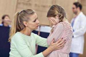 Little girl is crying while with her mother at a doctor on consultation photo