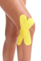 Picture showing special physio tape put on injured knee over white background photo