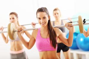 Group of smiling people lifting barbells photo