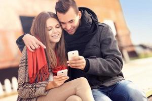 Young couple sitting on a bench and using smartphones photo