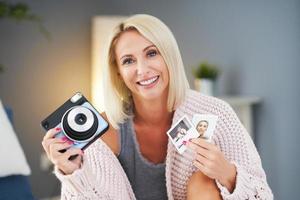 Adult beautiful woman taking instant photo at home