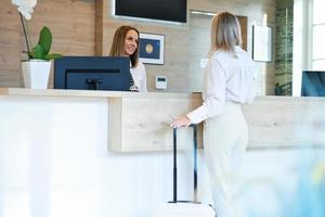 Receptionist and businesswoman at hotel front desk photo