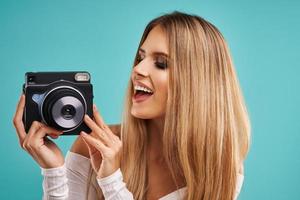 Beautiful adult woman posing over blue background taking instant photos