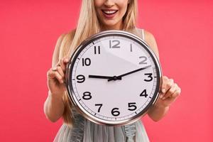 Beautiful adult woman posing over pink background with clock photo