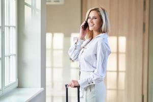 Businesswoman with luggage in modern hotel lobby photo