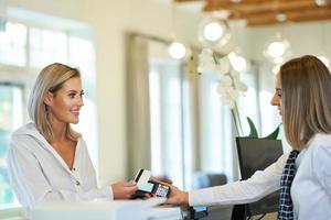 Receptionist and businesswoman at hotel front desk photo