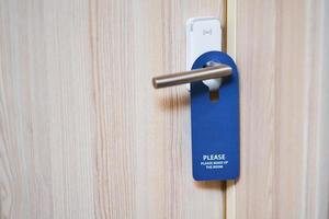 Blue plate hanging on the door handle of a hotel room photo