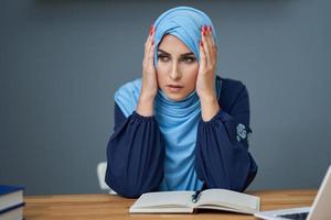 Unhappy muslim female student learning at home photo