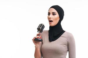 Muslim woman singing with microphone over white background photo