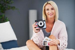 Adult beautiful woman taking instant photo at home