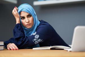 Unhappy muslim female student learning at home photo