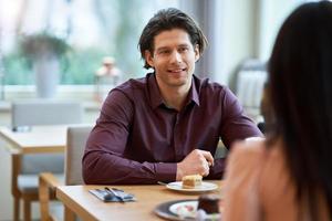 Young Couple Enjoying Coffee And Cake In Cafe photo