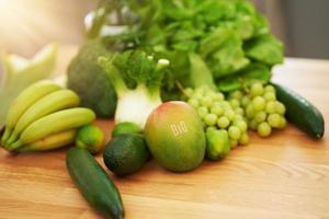 Fresh green fruit and vegetables on wooden counter photo