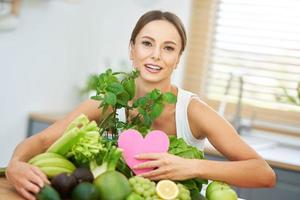 mujer adulta sana con comida verde en la cocina foto