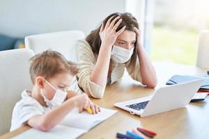 Boy and exhausted mother trying to work at home during coronavirus pandemic photo