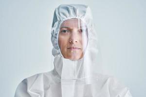 mujer con traje de riesgo biológico y protector facial sobre fondo blanco. foto