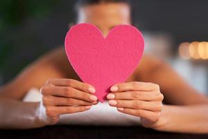 Relaxed woman waiting for a back massage and holding heart photo