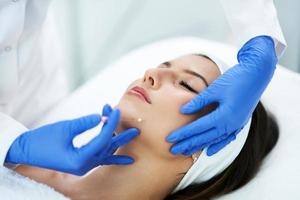 Beautiful young woman getting polydioxanone thread lifting at beauty salon. photo