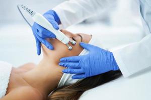 Beautiful young woman getting face treatment at beauty salon. photo