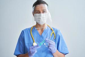 Doctor holding covid-19 coronavirus vaccine over light background photo