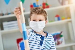 Adorable little boy in kindergarten with mask on due to coronavirus pandemic photo